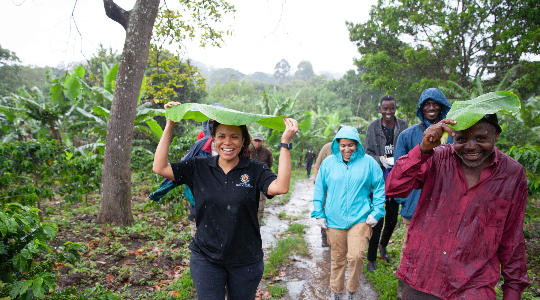 People happily walk through a rainforest as rain pours on them.
