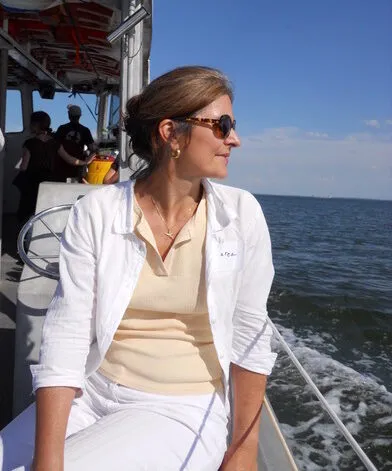 A person sitting on a boat, looking over her shoulder into the ocean.