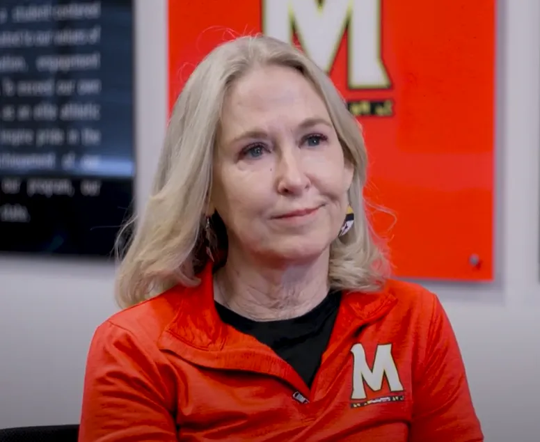 A person wearing a red quarter zip pullover with a white M logo on it.