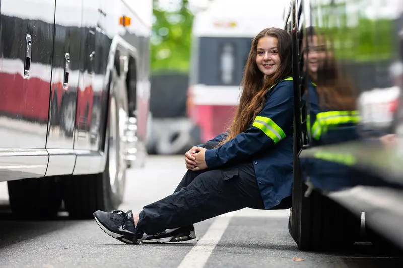 A person in firefighter gear leaning up against a vehicle.