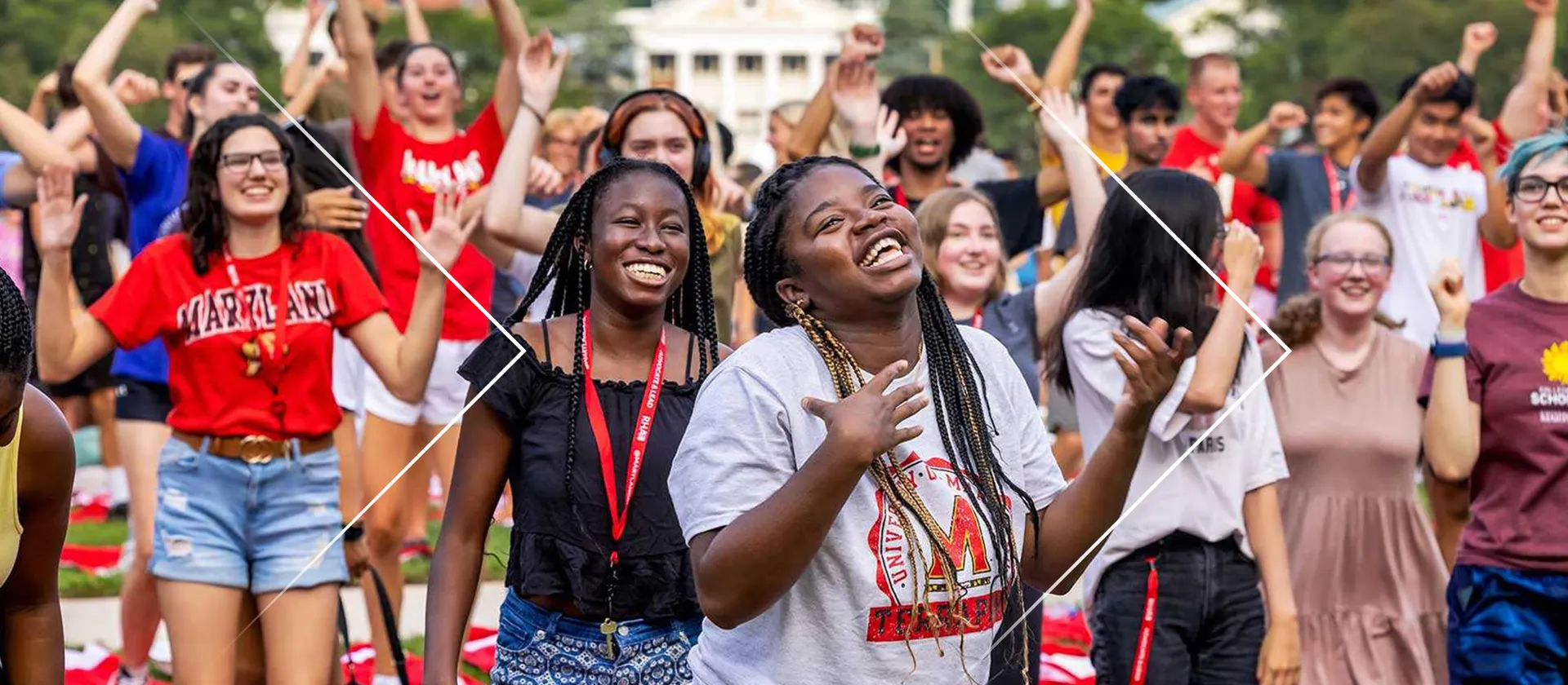 Many students at the University of Maryland are smiling with their arms raised in poses of celebration.