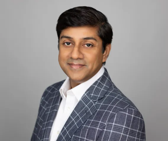 A person smiling while wearing a white shirt and a gray sport coat.