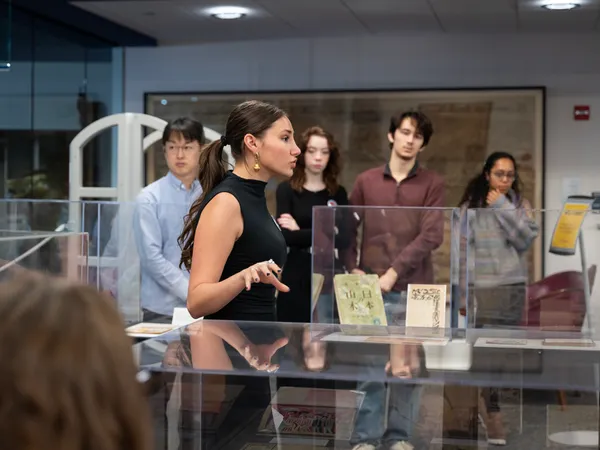 A woman in a black shirt motions as she speaks to a crowd of people inside a University of Maryland library.