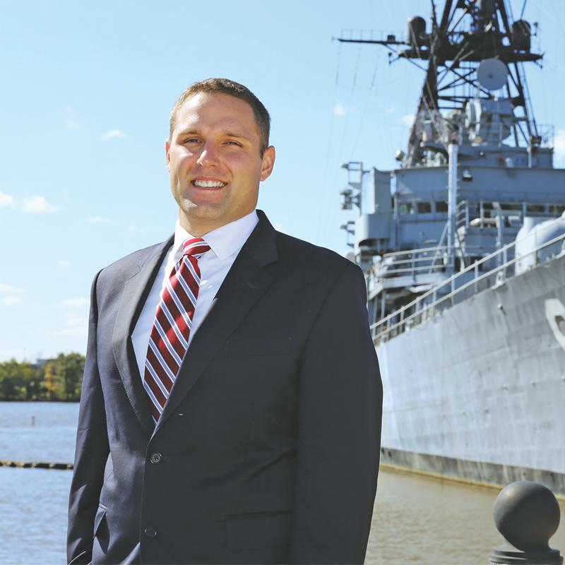 man in business attire standing in front of a ship