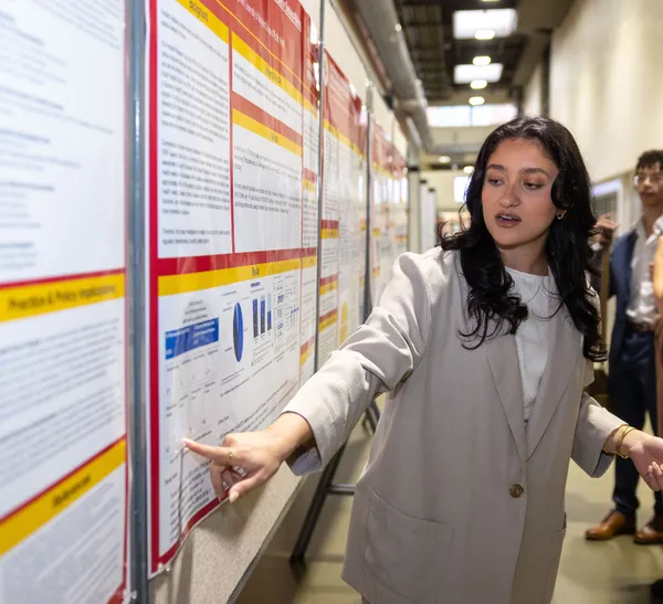 A woman points to text on a poster as others look on.