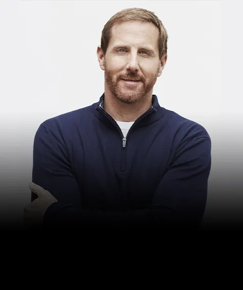 A man stands with his arms crossed in front of his chest.