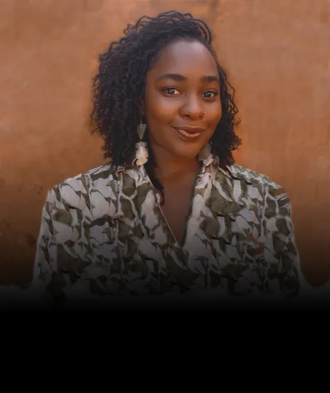 A headshot of a person smiling, wearing a green and white shirt.