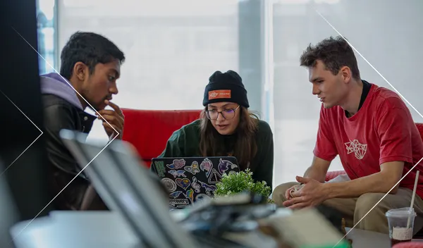 Students at laptop looking at someone writing at a whiteboard