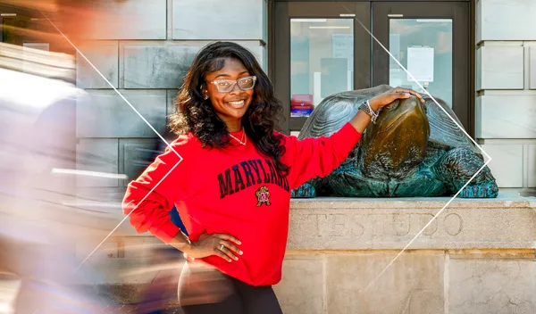student posing with her hand on Testudo, other students motion blur around